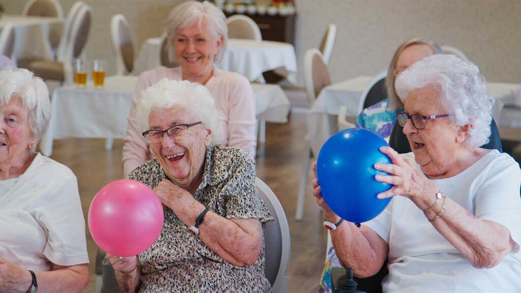 Social worker meeting with an older resident and family member in a bright assisted living room.
