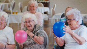 Social worker meeting with an older resident and family member in a bright assisted living room.